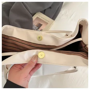 Detail view of large tote bag with magnetic snap closure and striped interior lining