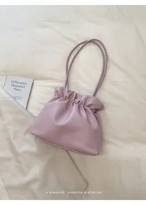 Close-up of lavender pleated bucket bag made of textured leather on white fabric