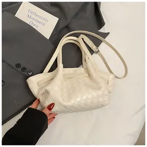 Détail du sac seau en cuir blanc tressé montrant la texture et la bandoulière réglable