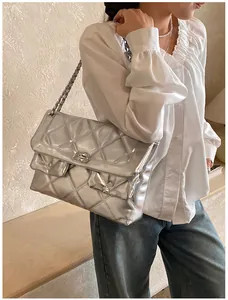 Detail of silver metallic quilted handbag featuring chain strap and textured diamond pattern