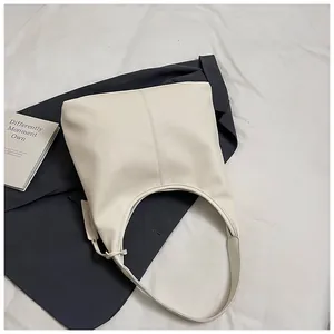 Gros plan sur le sac hobo crème avec texture litchi et étiquette en cuir