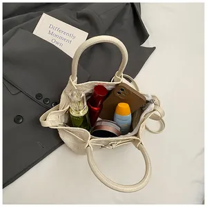Vue intérieure du sac seau tissé beige montrant le rangement pour maquillage et mobile