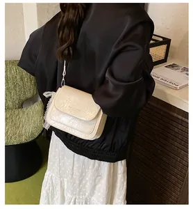 Detailed view of cream textured leather crossbody bag with white lace trim detail