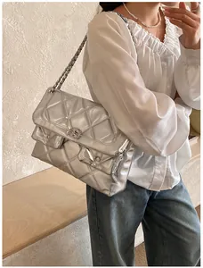 Close-up of silver quilted crossbody bag with metal chain strap on female model