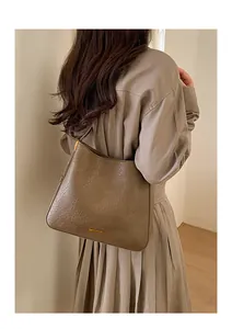 Détail du sac hobo marron foncé à texture vintage avec logo en métal doré sur modèle