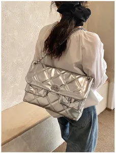 Detailed side view of silver quilted shoulder bag with chain strap on a model