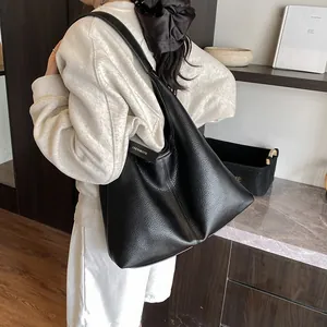 Grand sac cabas noir avec grain de litchi porté par un mannequin pour style chic