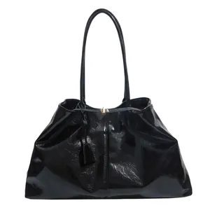 Glossy black large tote bag with top handles and gold buckle on white background