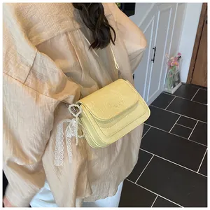 Detail of yellow oil-wax leather mini bag with pearl heart and lace bow charm