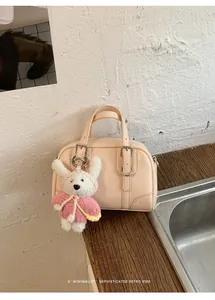 Dettaglio borsa bowling crema con cinturini e ciondolo a forma di coniglio peluche