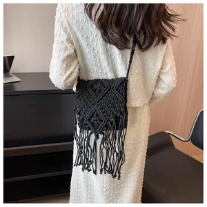 Detail of bohemian black hand-woven straw bag featuring intricate tassels and diamond pattern