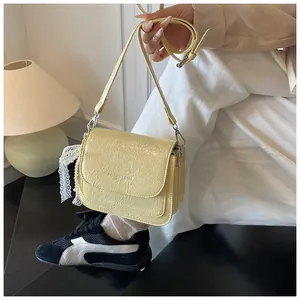 Detail of pale yellow leather square crossbody bag with lace and beaded accessories