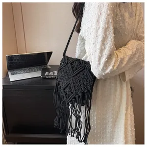 Detail of hand-woven black macramé crossbody bag featuring long bohemian style fringe