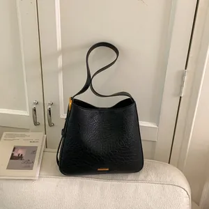 Sac seau minimaliste noir à motif litchi avec logo doré et style vintage élégant