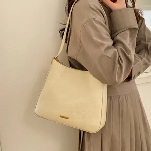 Sac hobo blanc crème minimaliste avec texture cuir plissé et plaque logo en métal doré