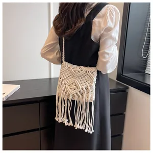Detail of bohemian woven straw bag showing intricate diamond patterns and long cotton tassels