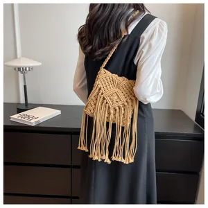 Detail of bohemian beige woven crossbody bag with long fringes shown on a model