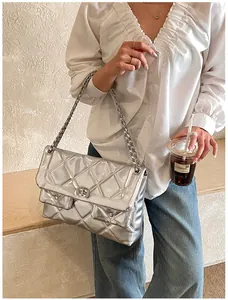 Detail of silver quilted chain bag with metallic finish and metal turn-lock closure