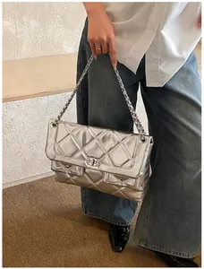 Detailed close-up of a silver quilted chain bag with a metal turn-lock and dual front pockets