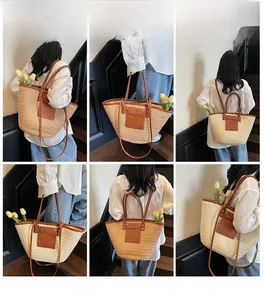 Detail view of large straw tote bag with brown leather handles and a front pocket