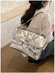 Detail of silver quilted chain bag featuring metallic texture and turn-lock closure