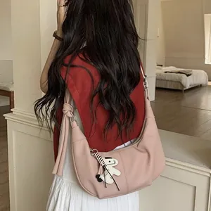 Pink minimalist half-moon hobo bag with cartoon dog charm worn by a model