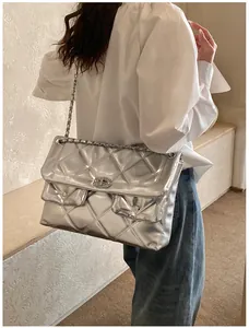 Detail of silver quilted texture and metal chain strap on a large shoulder bag