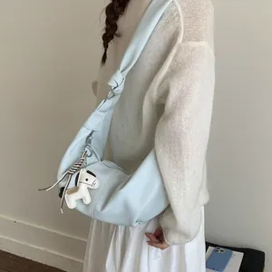 Minimalist light blue hobo bag with knot strap and horse charm worn on shoulder