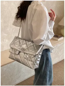 Detail of silver quilted crossbody bag with metal chain strap and turn-lock closure