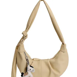 Minimalist beige crescent bag in pebbled leather with knotted strap and horse charm