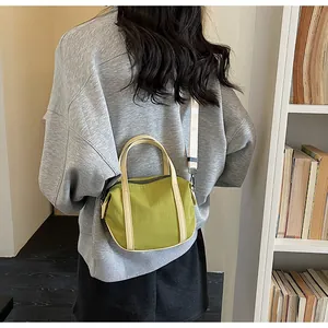 Green mini canvas bag shown on model featuring a detachable strap and a soft pillow shape