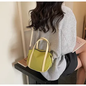 Olive green nylon crossbody bag with beige faux leather handles and detachable strap
