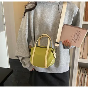 Detail view of avocado green nylon crossbody bag with creamy leather trim and strap