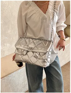 Silver quilted chain bag shown on model with dual front pockets and metallic finish