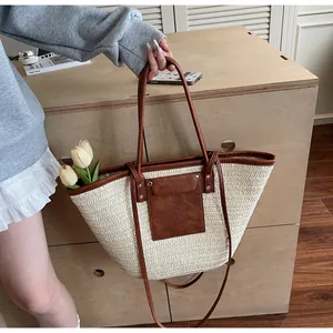 Detail view of woven straw tote bag with brown leather handles and square pocket detail