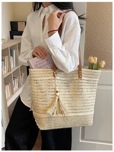 Dettaglio della borsa tote in paglia con trama traforata, nappe e manici in pelle marrone
