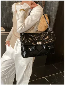 Detail of black quilted chain bag featuring dual front pockets and silver twist locks