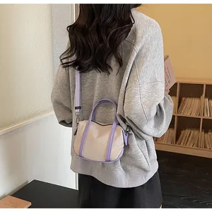 Detail of model wearing the cream canvas tote with purple leather straps and zip closure