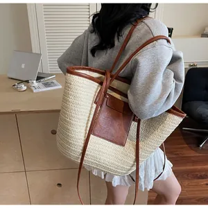 Detail of straw woven tote bag with brown faux leather trim shown in a lifestyle scene