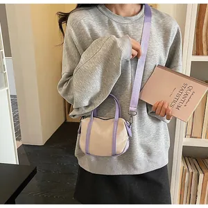 Detail view of a mini canvas crossbody bag with purple handles and a matching woven strap
