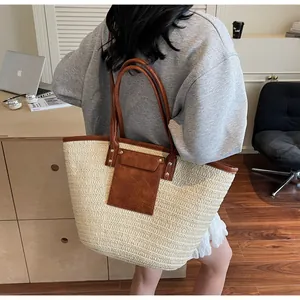 Detail of straw tote bag with brown leather handles and large storage capacity