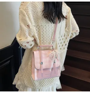 Detalle de bolso rosa a cuadros con lazo de encaje y colgante de perla en modelo