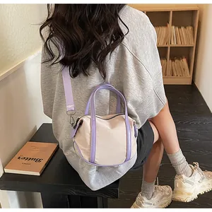 Detailed view of cream canvas crossbody bag with purple leather trim and wide strap