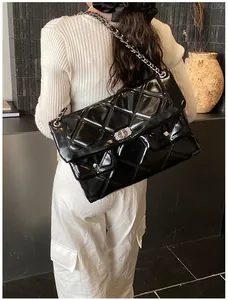 Detailed view of black quilted patent leather shoulder bag with silver chain strap