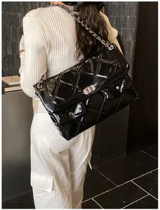 Detail showing glossy quilted leather texture and silver chain strap on black bag