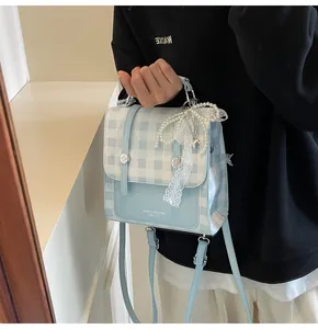 Detalle del mini bolso de cuadros azules con colgante de lazo de encaje y herrajes plateados