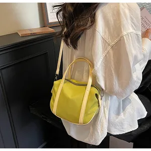 Detail view of mini avocado green nylon Boston bag with beige top handles and strap