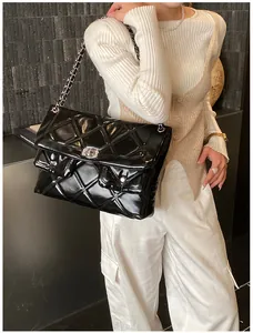 Close-up of black quilted shoulder bag with silver chain strap and metal swivel lock