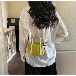 Lifestyle view of a matcha green canvas handbag with cream handles and adjustable strap