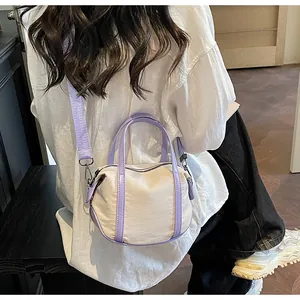 Detail of canvas crossbody bag with purple handles and wide fabric shoulder strap